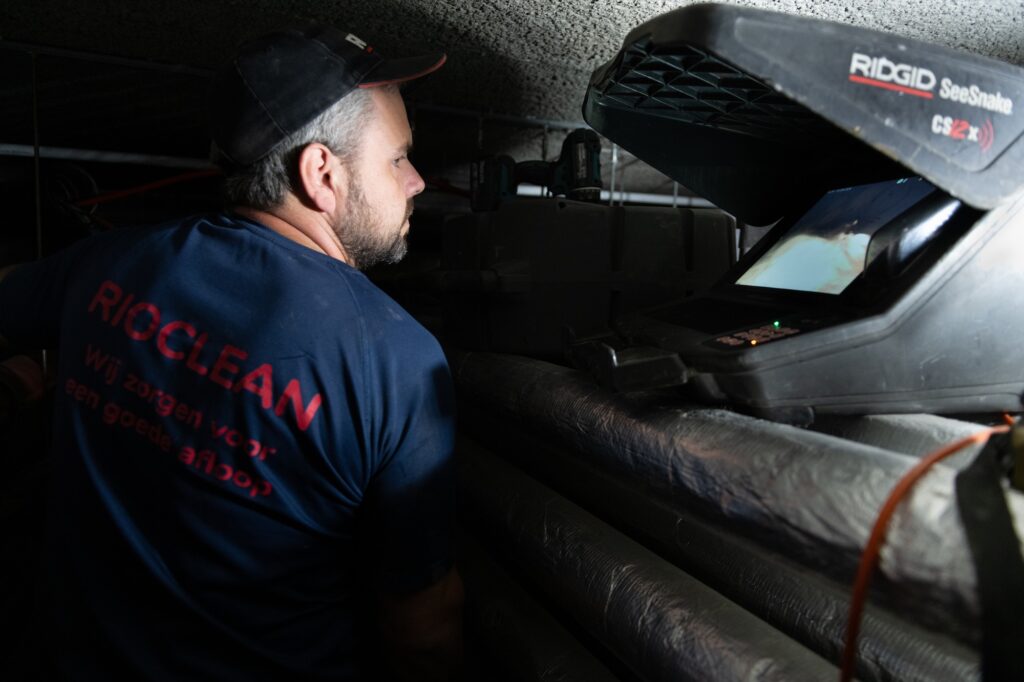 Rioclean-technicus bekijkt het camerabeeld van een rioolbuis op de inspectiemonitor