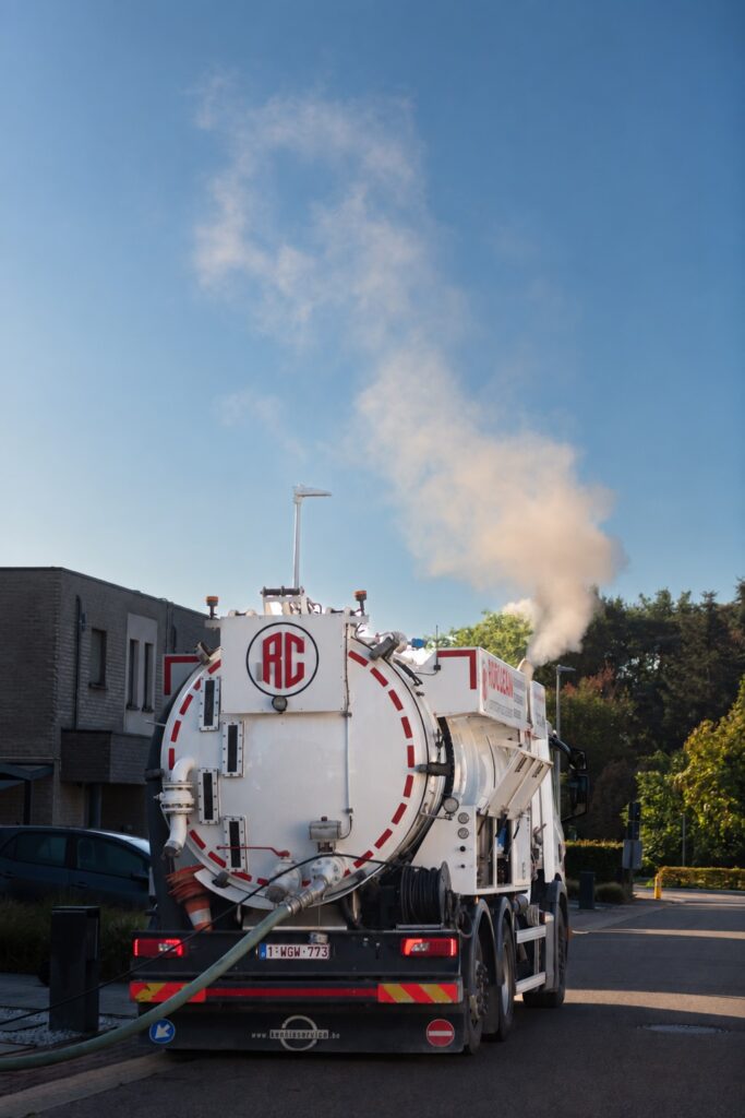 Rioclean-ruimwagen aan het werk in een woonstraat met de zuigslang aangesloten