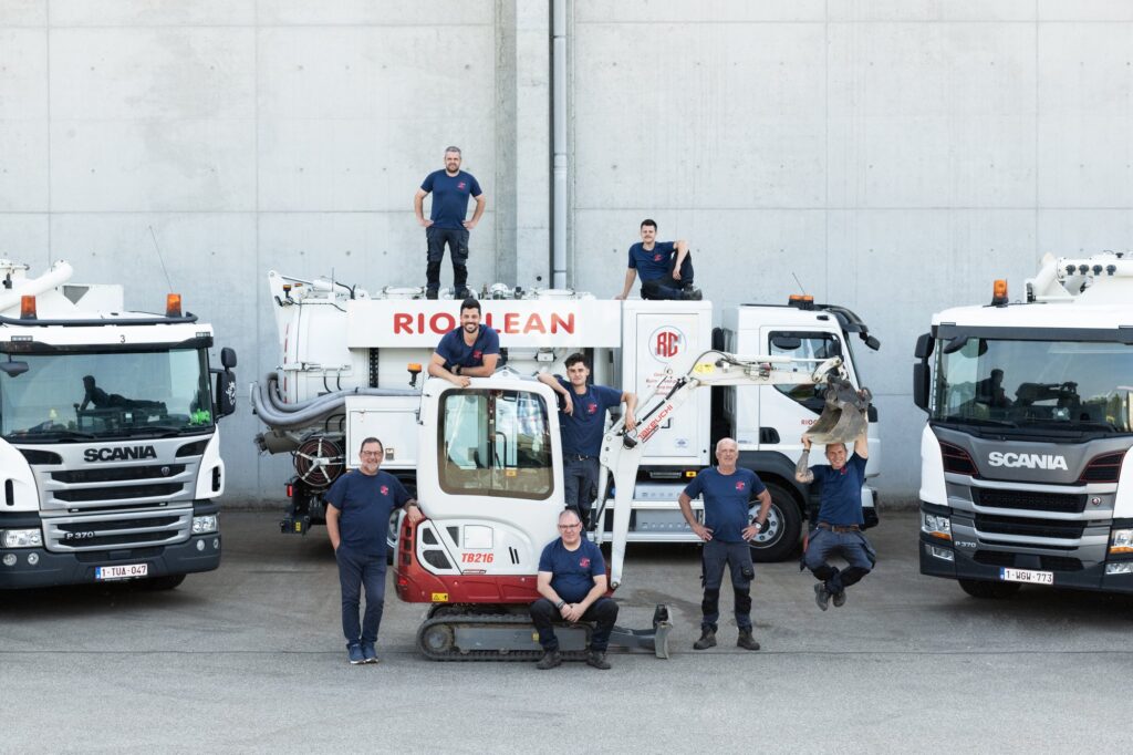 Het Rioclean-team tussen de ruimwagens en de minigraver op de bedrijfssite
